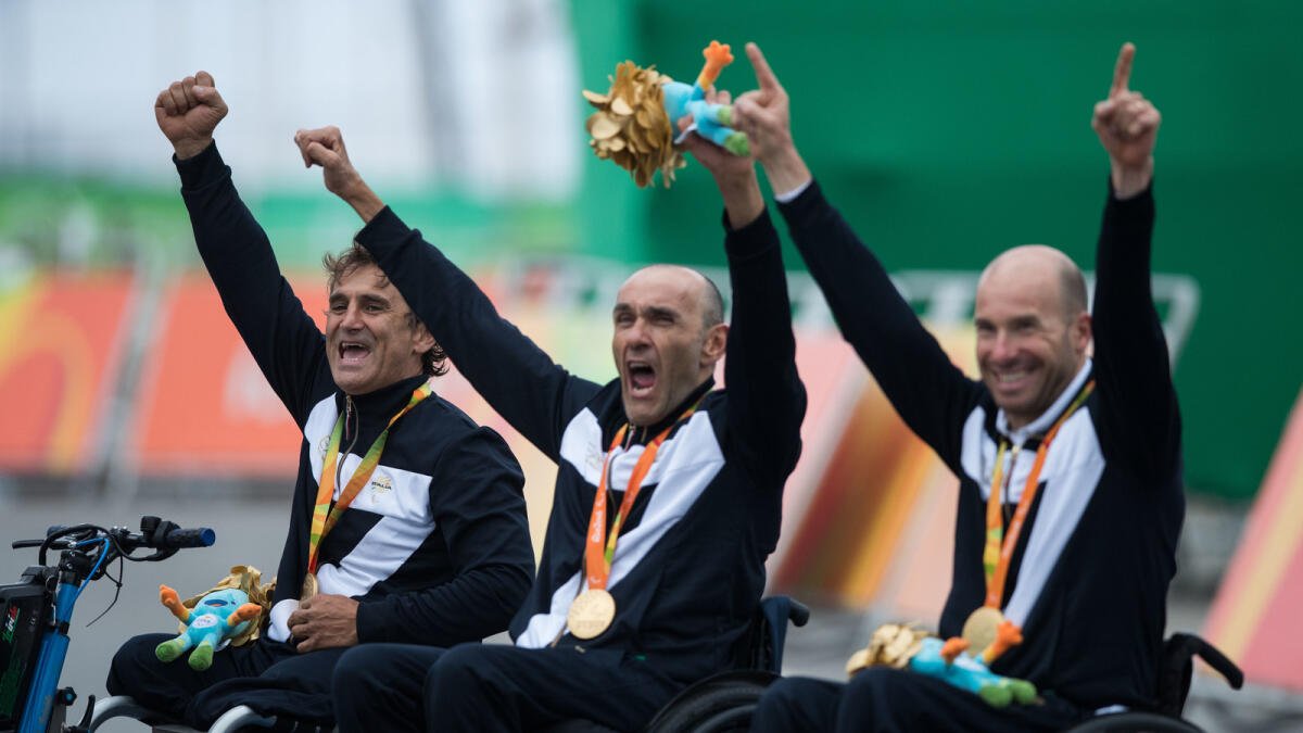 Italy's Vittorio Pedestal, Luca Mazzone and Alessandro Zanardi celebrate the gold medal in Cycling Road Men's Team Relay H2-5 final in the Rio 2016 Paralympic games at Pontal beach in Rio de Janeiro, Brazil, Sept. 16, 2016. (AP Photo/Mauro Pimentel)